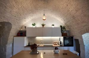 a kitchen with white cabinets and a stone wall at Villa Filou in Santa Lucia