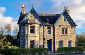 an old brick house with a blue door at Craigbuie Guesthouse in Killin