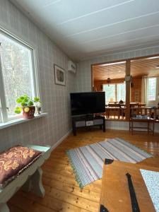 a living room with a flat screen tv and a table at The Hunters Hill - Cosy private forest retreat in Brålanda
