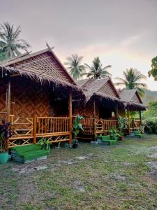 a group of huts with palm trees in the background at Kohmook Money RUEAN PHAI in Trang