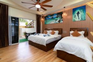 a bedroom with two beds and a ceiling fan at Hidden Tide Villa in Ukulhas