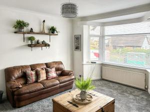 a living room with a brown leather couch and a table at Highcross in Poulton le Fylde