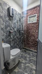 a bathroom with a toilet and a stone wall at Bird Park Villa Ella in Ella +39 photos