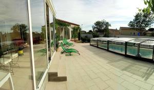 a patio with green benches and a swimming pool at Le Clos des Galets in Meynes