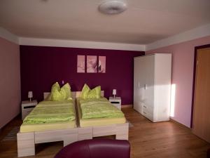 a bedroom with two beds and a purple wall at Ferienwohnung Wieck Greifswald in Wieck