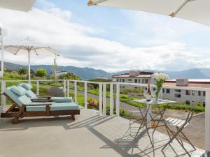 a patio with a table and chairs and an umbrella at Arc Guest House in Simonʼs Town