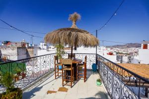 a balcony with a table and a straw umbrella at Riad Dar Home in Tétouan