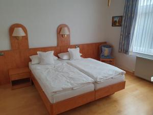 a bedroom with a large bed with white sheets and pillows at Hotel Flora in Bad Harzburg +6 photos