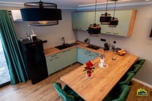 eine Küche mit einem Holztisch und grünen Stühlen in der Unterkunft EMC Hill in Dealu