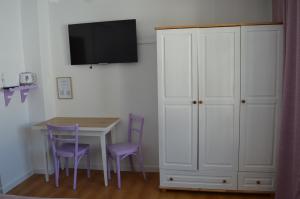 a dining room table with purple chairs and a white cabinet at Mojone Izby in Maruszyna