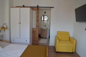 a bedroom with a bed and a yellow chair at Mojone Izby in Maruszyna