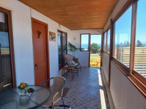 a balcony with a glass table and chairs on it at Cabañas Bellavista del mar in De Cauquenes