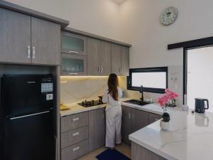a woman standing in a kitchen with a counter at TITANIUM 9 Villa in Tlekung