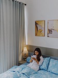 a woman sitting on a bed looking at her cell phone at TITANIUM 9 Villa in Tlekung