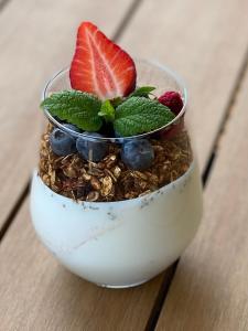 a bowl of granola with strawberries and blueberries at GreenWood Vendégház in Siófok
