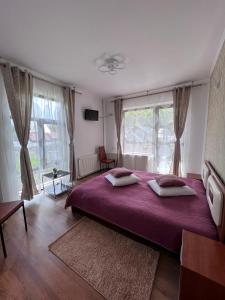 a bedroom with a large bed with a purple blanket at Pensiunea Silvian in Cheia