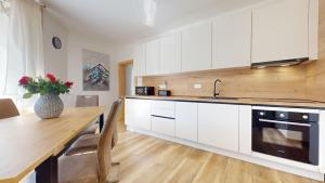 a kitchen with white cabinets and a table with a vase of flowers at Apartmán Timea v Terchovej in Terchová