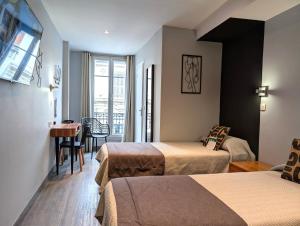 a hotel room with two beds and a table at H33 Hôtel in Nice