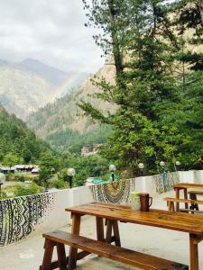 a wooden picnic table on a balcony with mountains in the background at Parbati Headquarters in Kasol