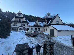 a car parked in front of a house with snow at Pokoje "U Ani" in Leśnica