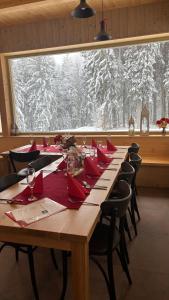 a long wooden table with red napkins and chairs and a large window at Horská chata Libín in Prachatice +12 photos