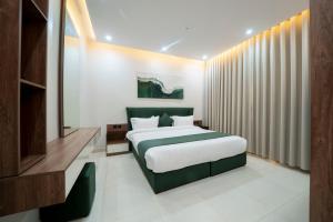 a bedroom with a large bed with a green headboard at اسوار بلس - Aswar Plus in Tabuk +25 photos