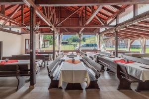 a dining room with tables and chairs and windows at Pensiunea Popasul Ursilor Medve Barlang Peștera Urșilor in Chişcău