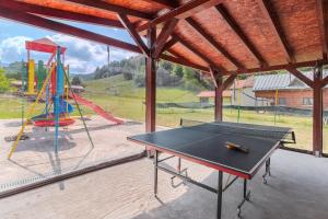 a ping pong table in front of a playground at Pensiunea Popasul Ursilor Medve Barlang Peștera Urșilor in Chişcău