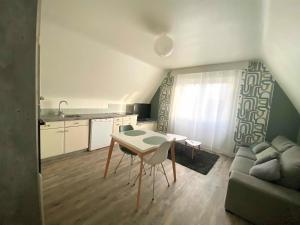 a kitchen and a living room with a table and a couch at Appart 2 Chambres, Centre Ville, Parking privé clos, Local vélo in Mayenne