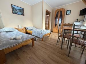 a room with two beds and a table and chairs at Pokoje "U Ani" in Leśnica