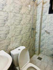 a bathroom with a toilet and a shower at Chambre avec salle de bain privative proche de la plage et de Saly in Mbour +11 photos