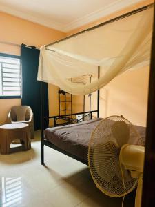 a bedroom with a canopy bed and a chair at Chambre avec salle de bain privative proche de la plage et de Saly in Mbour