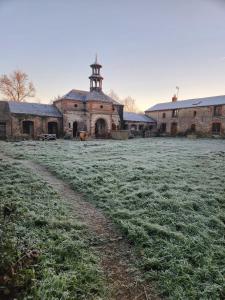 an old brick building with a clock tower in a field at Gite d'exception au Château in Le Fief-Sauvin