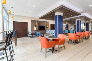 a dining area with orange chairs and tables in a lobby at Holiday Inn Express & Suites - Houston NW - Cypress Grand Pky by IHG in Cypress