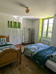 a bedroom with two beds and a lamp in it at Ferme Équestre Equi'Cantal in Montboudif