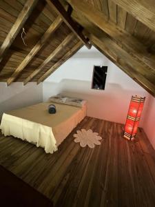a bedroom with a bed and a wooden floor at Casinha do Rosa in Imbituba