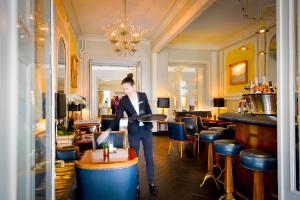 a man standing in a bar with a table in a room at La Résidence des Trois Couronnes in Vevey