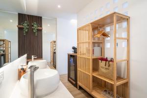 a bathroom with a white sink and a wooden shelf at Pico Samui in Bophut