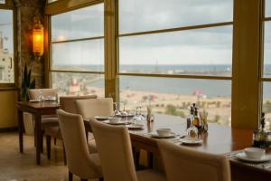 a dining room with a table and chairs and a large window at Marhaba Plaza Hotel in Tripoli