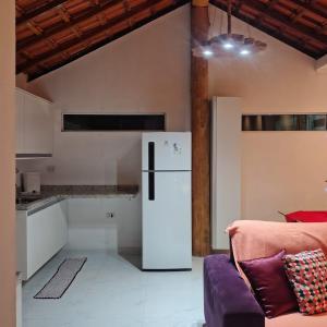 a kitchen with a white refrigerator and a purple couch at Chácara Sitara - Chalé Safira in Caldas