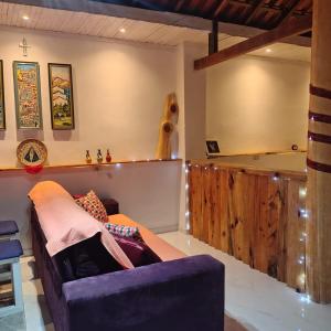 a living room with a purple couch and a shelf at Chácara Sitara - Chalé Safira in Caldas