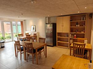 a kitchen with wooden tables and chairs and a refrigerator at Kyndestoft Bed & Breakfast in Holstebro