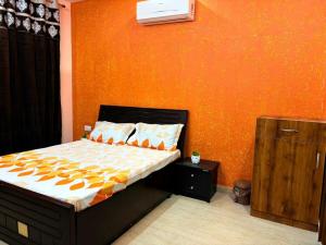 a bedroom with a bed and an orange wall at Good Vibes Retreat in Birbhaddar