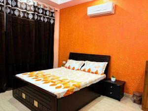 a bedroom with a bed with an orange wall at Good Vibes Retreat in Birbhaddar