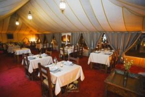 a dining room with tables and chairs in a tent at Merzouga Luxury Tents & Activities in Merzouga