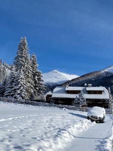 a car parked in the snow in front of a building at Oswald Lodge - surrounded by nature in Sankt Oswald