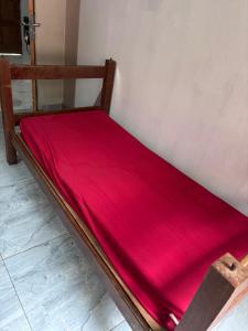 a wooden bed with a red sheet on it at Casa na Floresta in Santarém