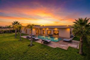 a house with a swimming pool and palm trees at Villa Dar E'Zwinna in Marrakesh