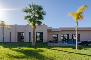 a house with palm trees in front of it at Villa Dar E'Zwinna in Marrakesh
