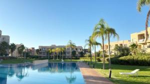 a swimming pool with palm trees and buildings at La Perle de Marrakech in Marrakesh